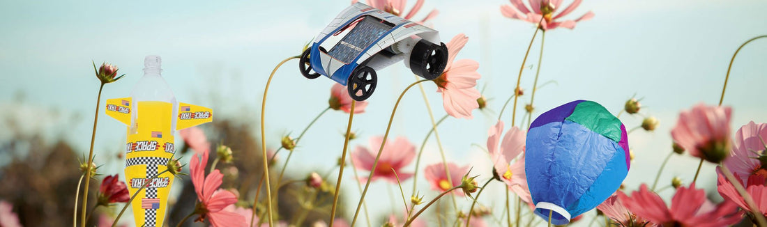 Solar car, a decorated bottle rocket and a blue and green hot air balloon among pink cosmos flowers