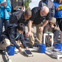 Teacher guiding students as they test a Ray Catcher solar vehicle, a renewable energy STEM kit for middle and high school classrooms and Junior Solar Sprint competition practice