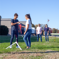 Two students learning STEM skills using the Pitsco Education AquaPort II Water Rocket Launcher outside of their middle school building