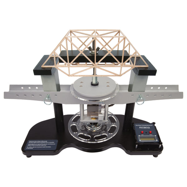 A Structures Testing Instrument with a turn-force wheel and a balsa wood bridge model on top, set on a black base with a digital load cell for measuring force.