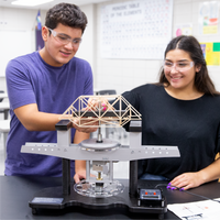 Two students in a classroom setting working on a STEM project testing their bridge with Pitsco Education's structure tester.