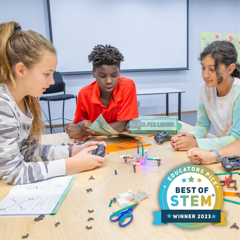 Three children engaged in a STEM activity with the Drone Maker Kit at a classroom table with educational materials, surrounded by 'Best of STEM' badge.