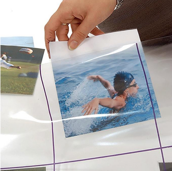 Hand holding a photo of a swimmer with a clear protective sheet over it